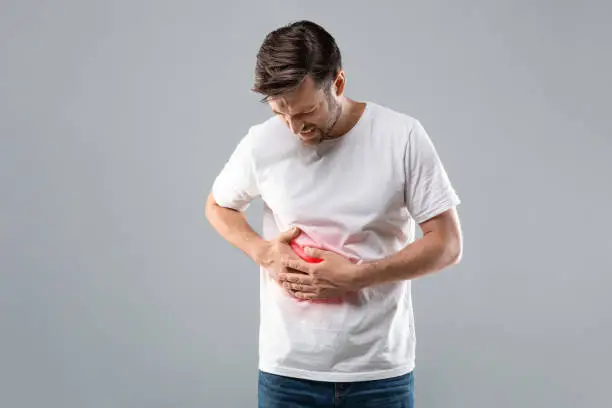 Man holding his abdomen in pain highlighting liver area, representing symptoms of liver disease or possible liver failure